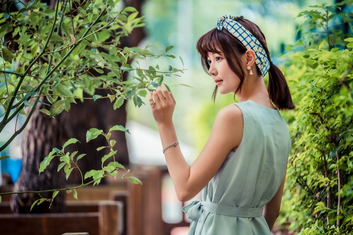 Asian woman with brown hair touching leaves