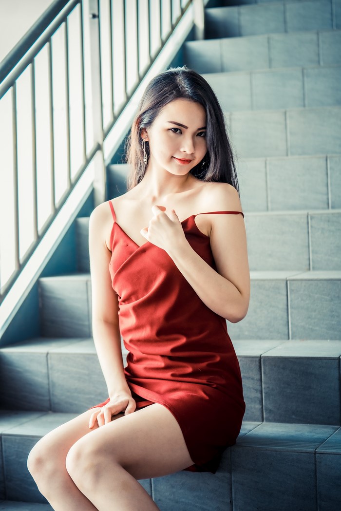 Asian woman in red dress sitting on stairs