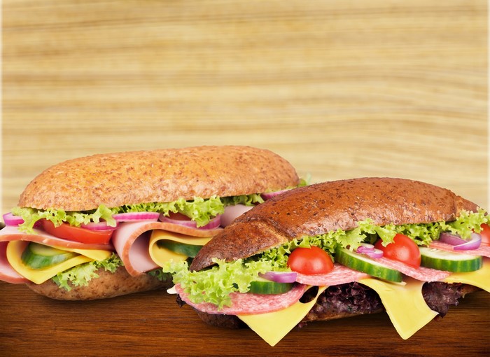 Two sandwiches with vegetables and sausage