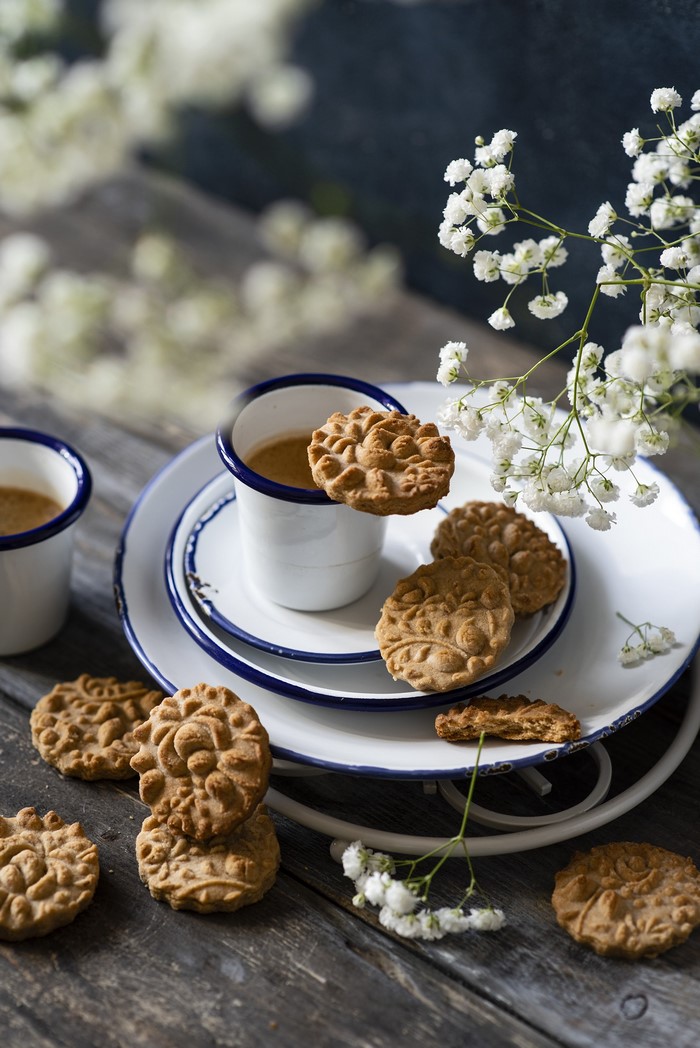 Coffee and cookies on wooden table with flowers