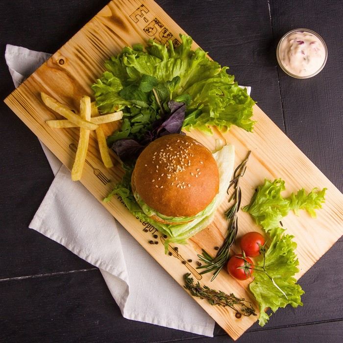 Hamburger with fries and salad on a wooden board
