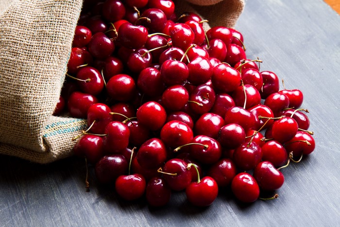 Cherries spilling from a burlap sack