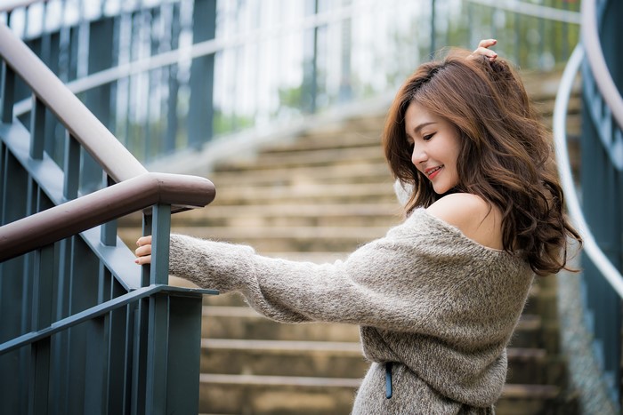 Brown-haired woman in sweater on stairs