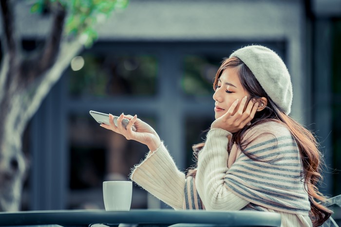 Asian woman in beret with smartphone and coffee