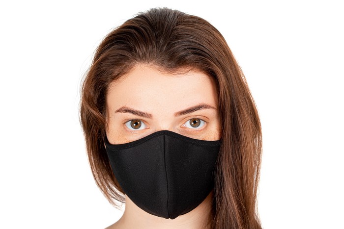 Woman wearing a black face mask on white background