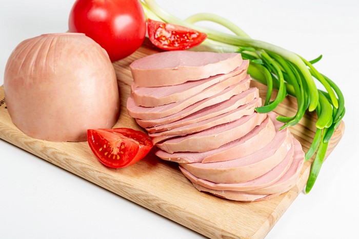 4K Sausage Slices with Tomatoes and Scallions on Cutting Board