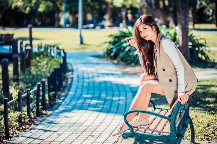 Asian woman sitting on a park bench