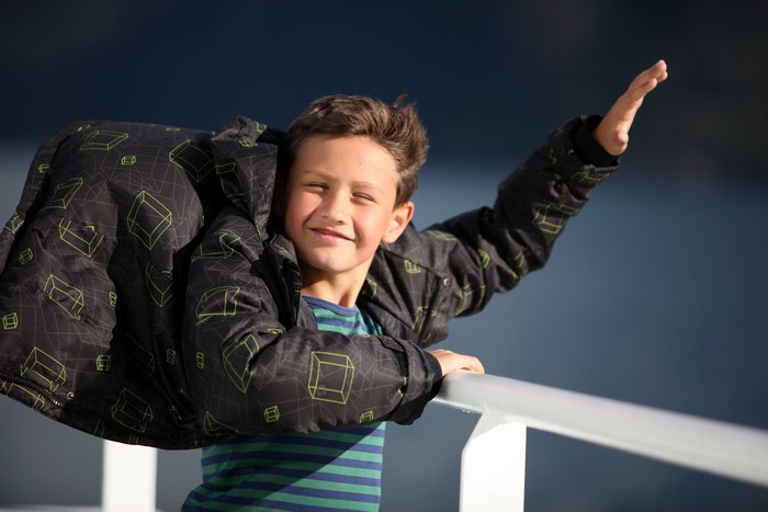 Boy in a patterned jacket waving