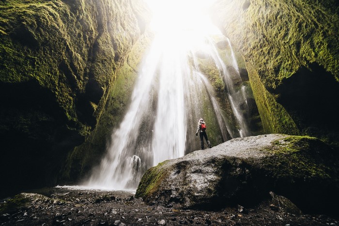 Tourist at a Mossy Waterfall in Iceland