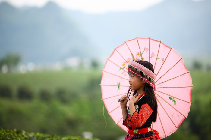 Girl in traditional clothing holding a pink umbrella