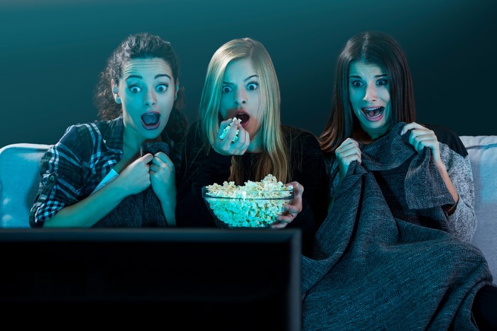 Three women watching TV with popcorn