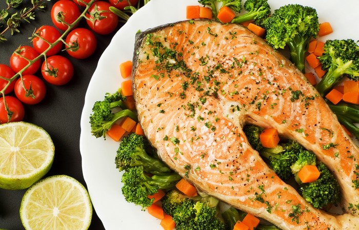 Salmon steak with broccoli, carrots, tomatoes, and lime