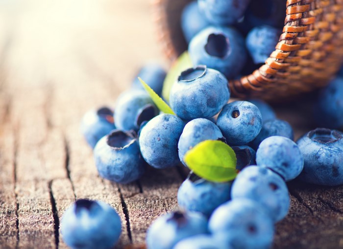 Blueberries spilling from a basket onto a wooden surface