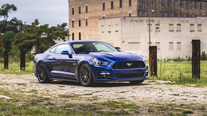 Blue Ford Mustang parked on gravel