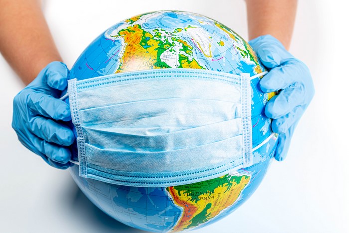 Globe with Face Mask Held by Hands in Gloves