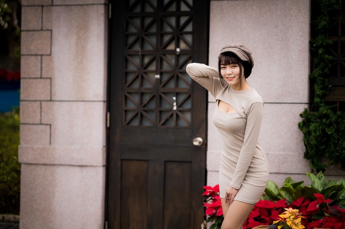 Asian woman in dress and baseball cap posing