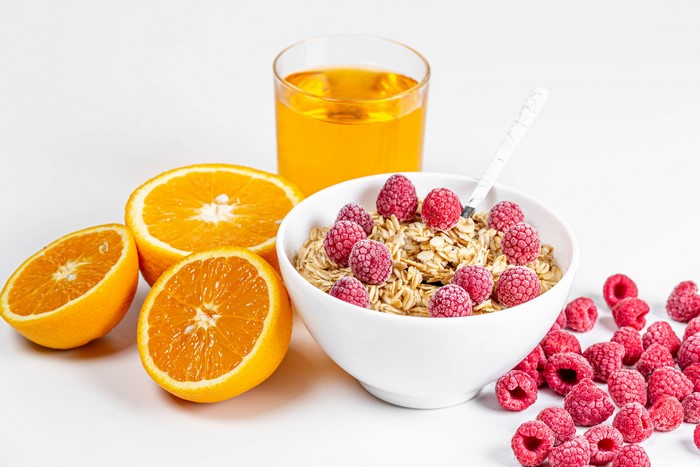 Bowl of muesli with raspberries, oranges, and juice
