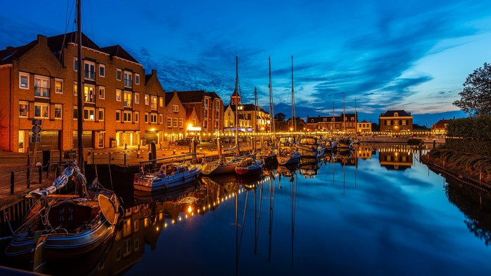 Boats docked at a canal waterfront in Willemstad, Netherlands at night