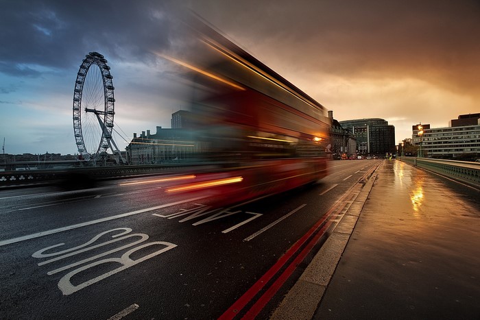 London Eye and a blurred red bus on a bridge at sunset
