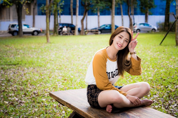 Asian woman sitting on a bench making peace sign