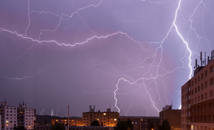 Lightning strikes over city buildings at night
