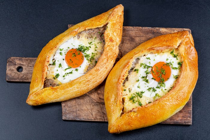 Two Khachapuri with Fried Eggs on Cutting Board