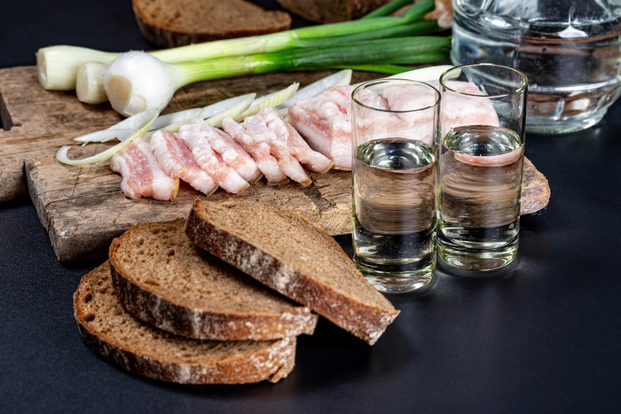 Salo, scallions, bread, and vodka shots on a cutting board