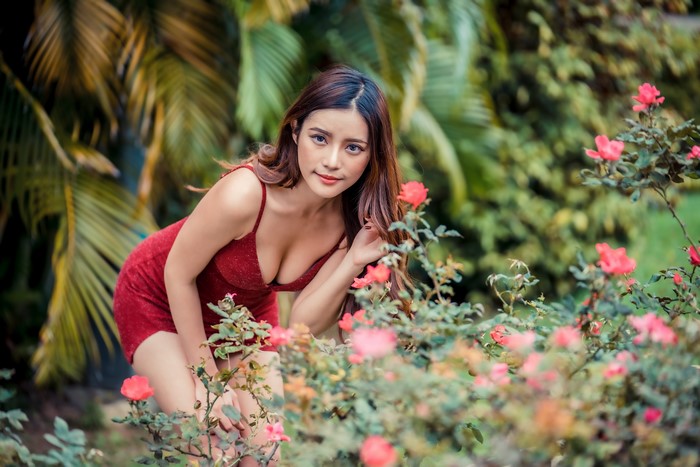 Asian woman in red dress posing near roses