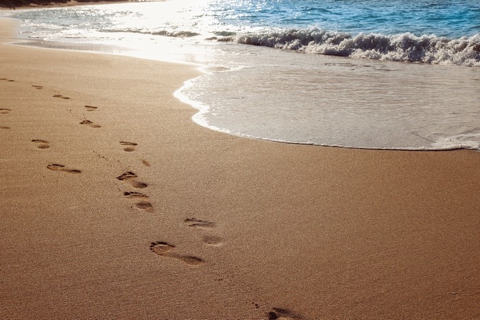 Footprints on a Sandy Beach with Waves