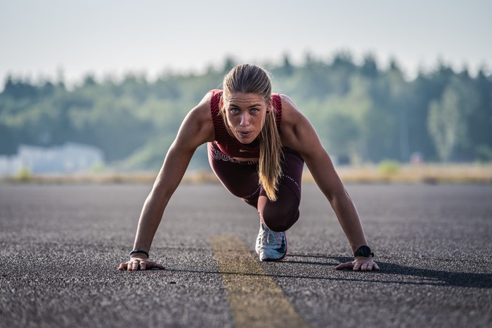 Woman in starting pose on asphalt