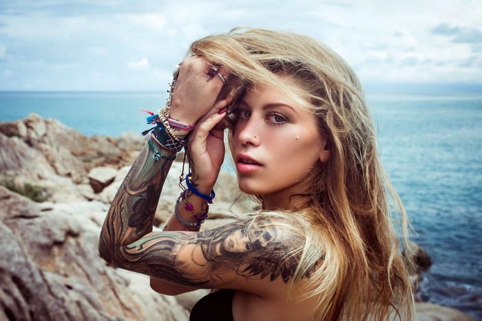 Woman with tattoos and bracelets by the sea