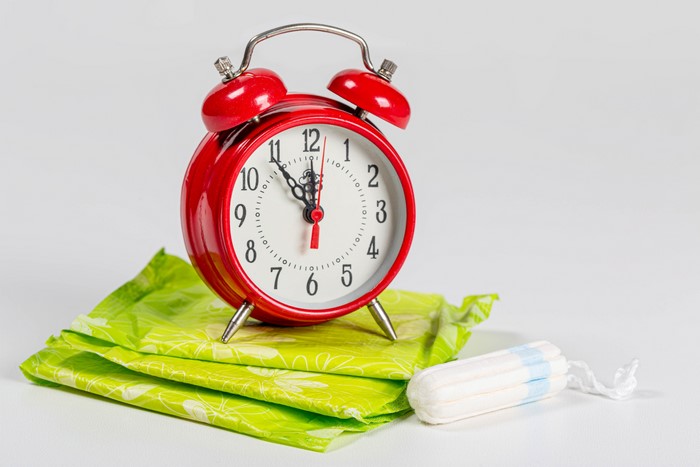 Red alarm clock on sanitary pads and tampon