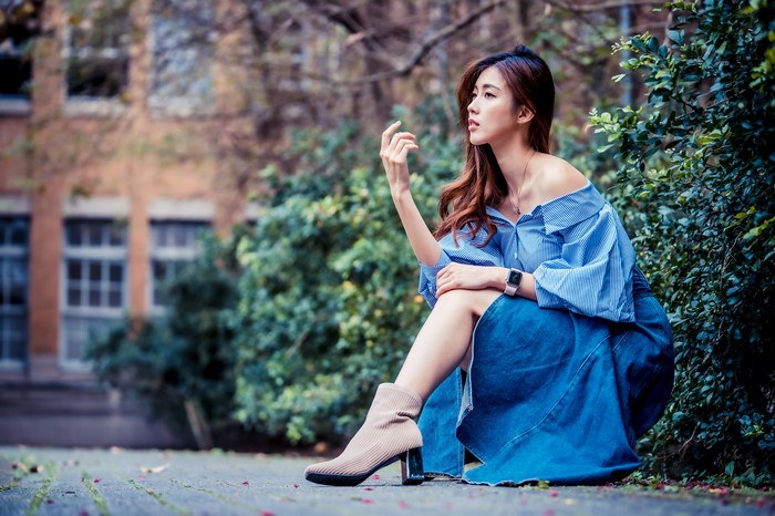 Asian woman sitting outdoors in a blue dress