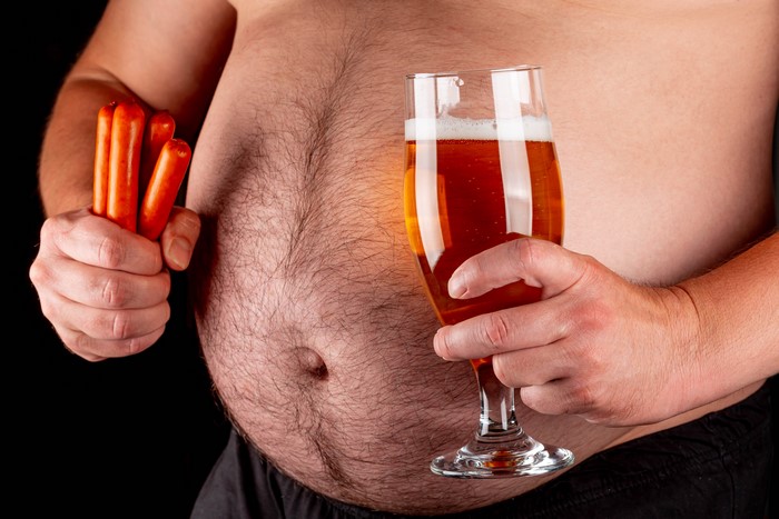 Man with large belly holding sausages and beer
