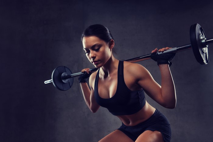 Brunette girl doing barbell squats