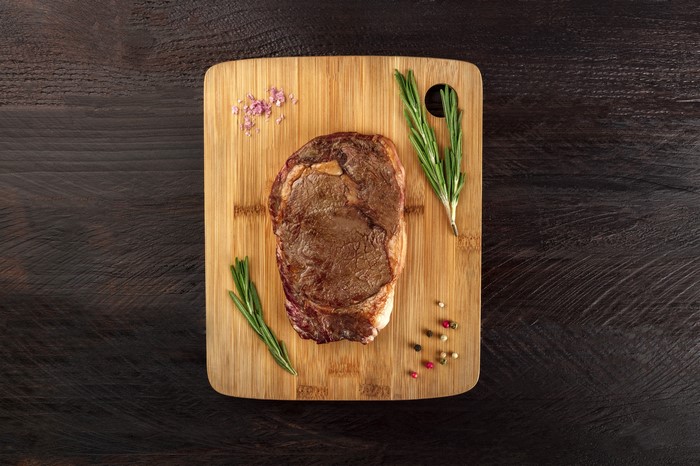 Raw steak with rosemary and spices on a cutting board