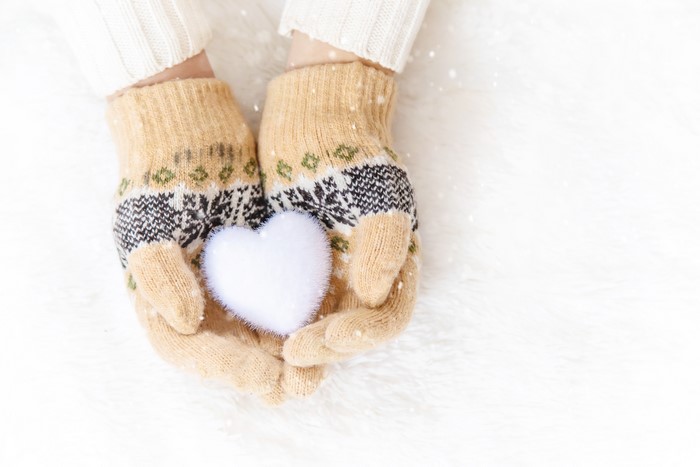 Hands in winter gloves holding a white heart