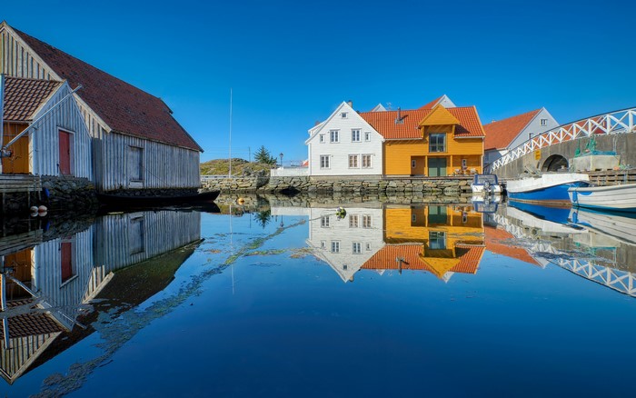 Houses and boats reflected in water in Skudeneshavn, Norway
