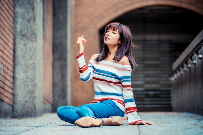 Asian woman sitting in jeans and sweater