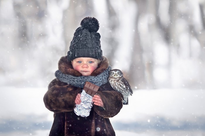 Child with owl and chocolate in winter