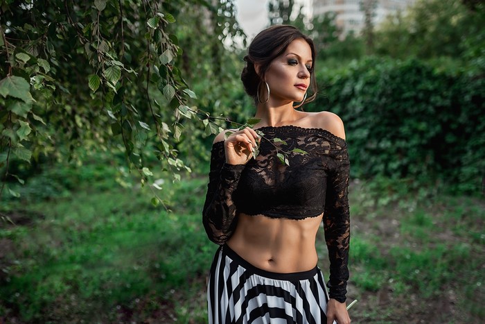 Model Georgiy Dyakov posing in a black lace blouse and striped skirt