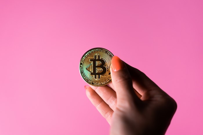 4K Bitcoin coin held by a hand with orange nails