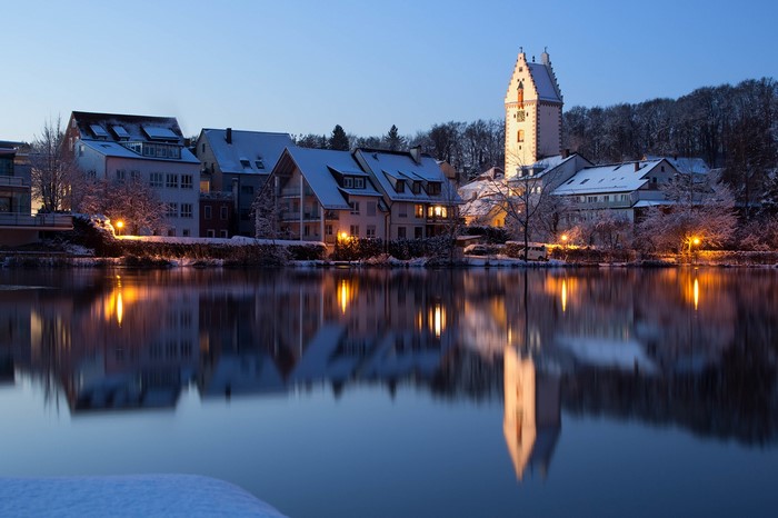 Houses and tower reflected in a lake at dusk in Germany