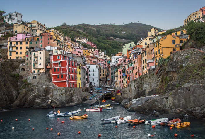 Riomaggiore, Italy - Colorful houses on a rocky coast with boats