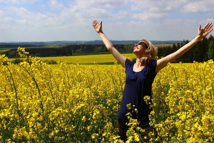 Woman with arms raised in a field of yellow flowers