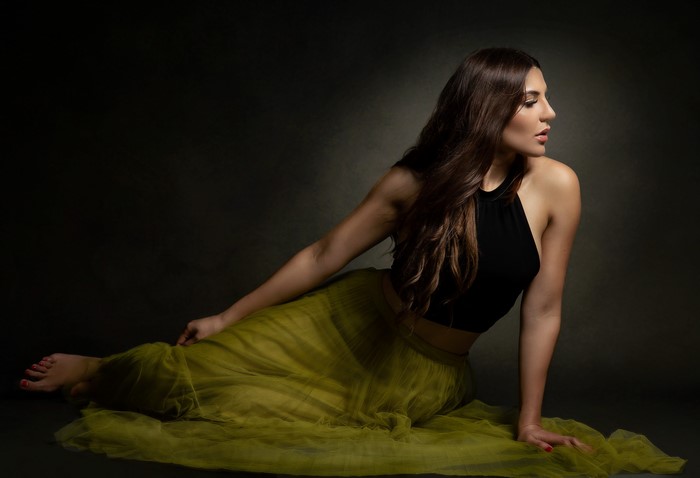 Priscila with long brown hair in a black singlet and skirt
