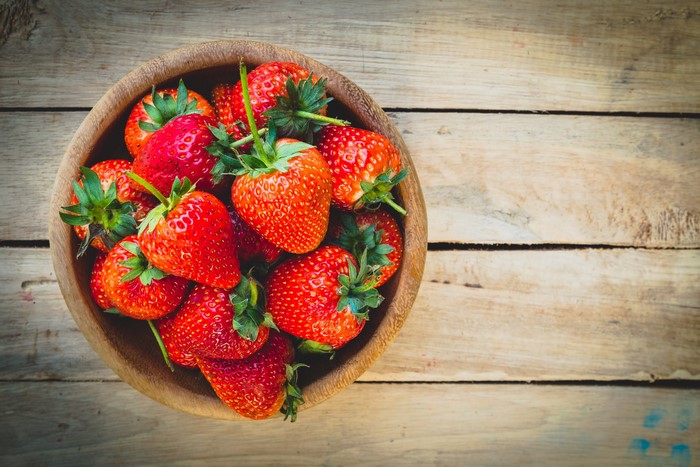 Bowl of strawberries on wooden planks