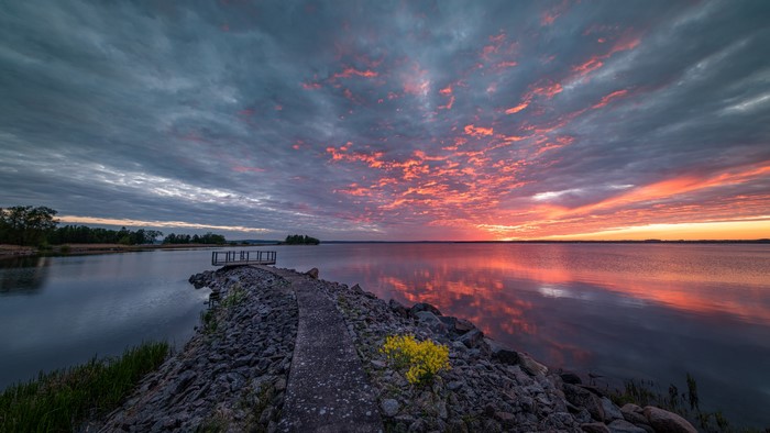 Sunset over a lake with a rocky pier