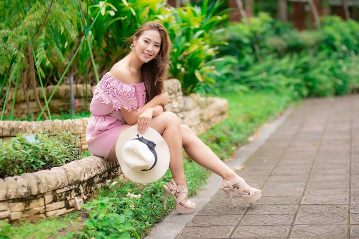 Asian woman sitting with a hat and stilettos