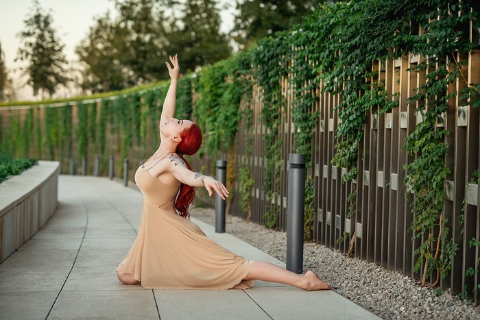Redhead dancer in a beige dress posing outdoors
